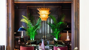 A well-lit lobby with a chandelier, seating area, and decorative plants. - Truitt Hotel (St. Louis)