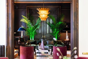 Un vestíbulo bien iluminado con candelabro, zona de estar y plantas decorativas.