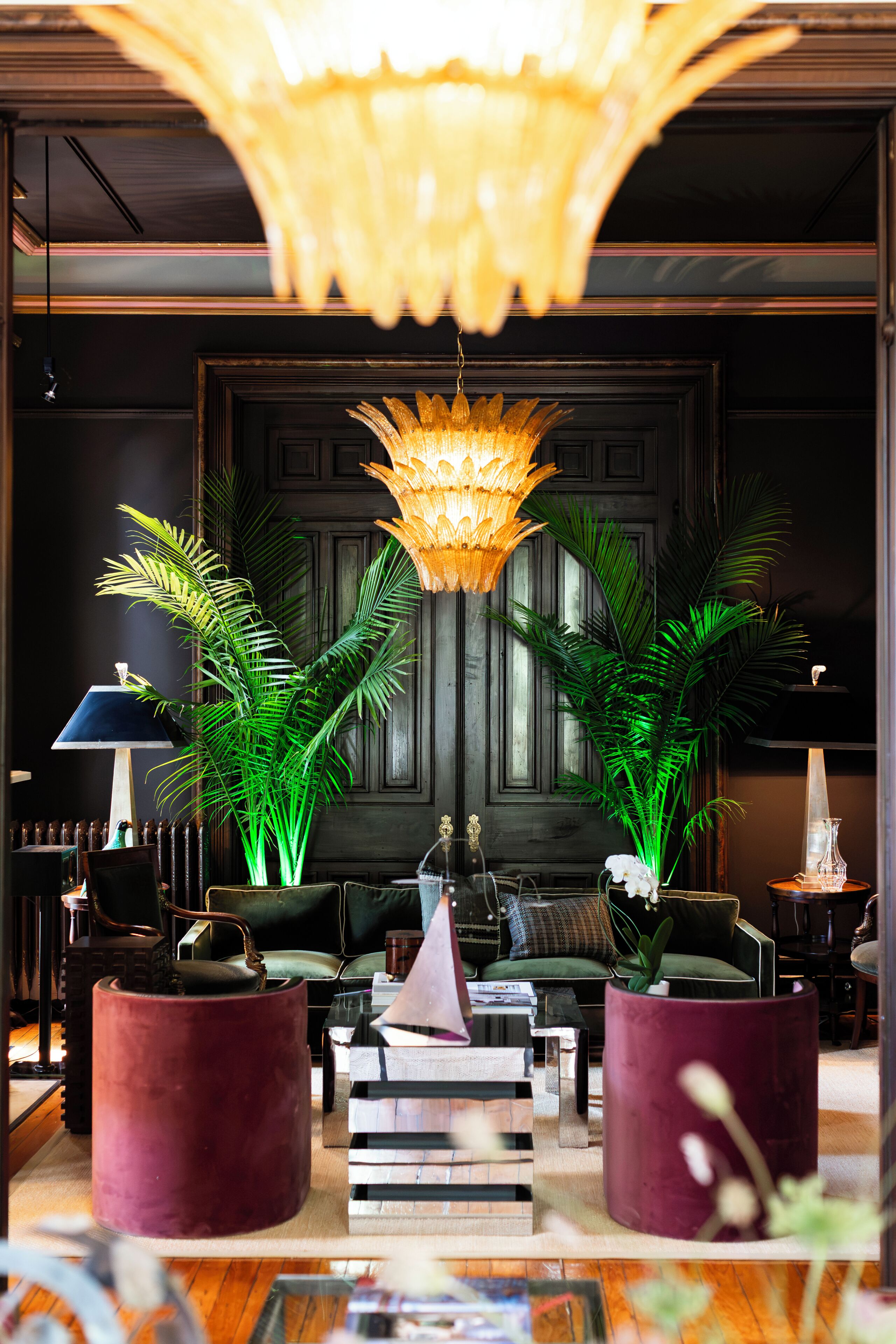 A well-lit lobby with a chandelier, potted plants, and a seating area.