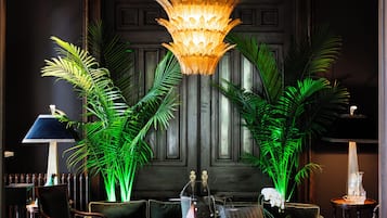 A well-lit lobby with a chandelier, potted plants, and a seating area.