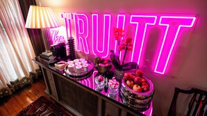 A bar area with a neon sign, a lamp, and various food and drink items. - Truitt Hotel (St. Louis)