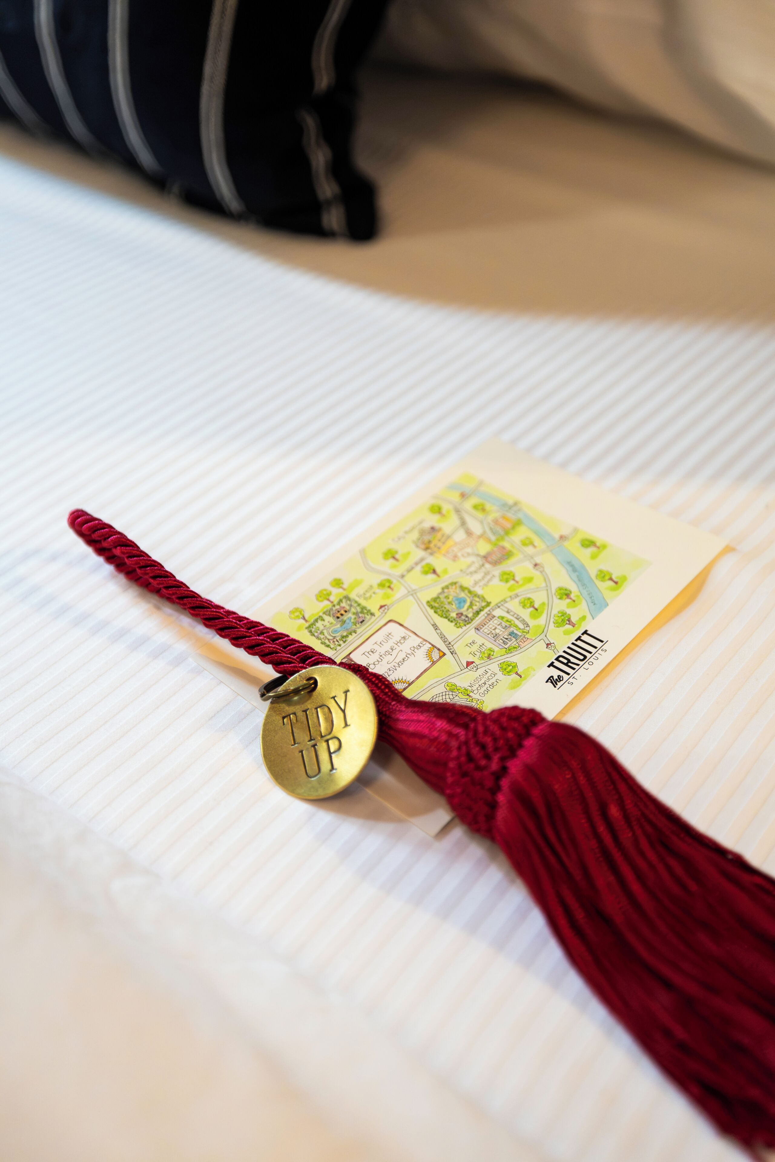 A bed with a neatly folded map and a tassel with a tag.