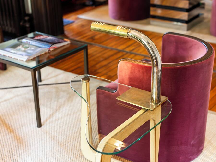 A modern interior with a glass table, a metal lamp, and a red upholstered chair.