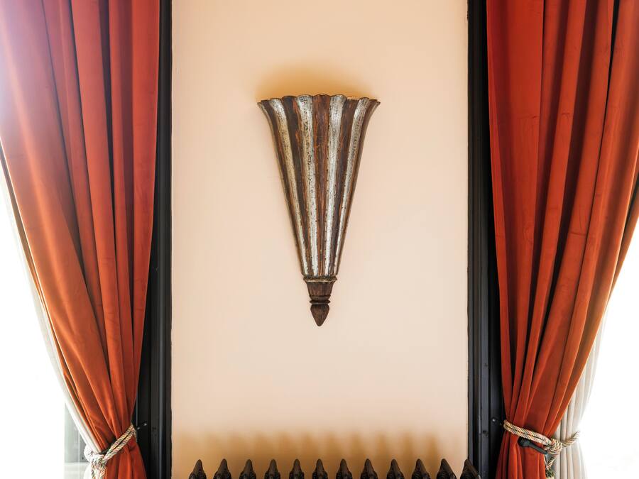 A room with a decorative wall piece, curtains, and a black metal fence.
