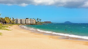 Une plage avec un hôtel, un ciel dégagé et des vagues sur l’océan.