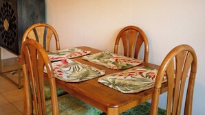 Une table de salle à manger en bois, accompagnée de quatre chaises, chacune dotée d’un siège rembourré de couleur verte.