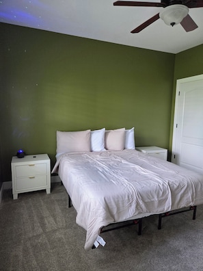 A bedroom with a bed, nightstands, a ceiling fan, and a wall-mounted light fixture. - Our Sango Retreat (Clarksville)