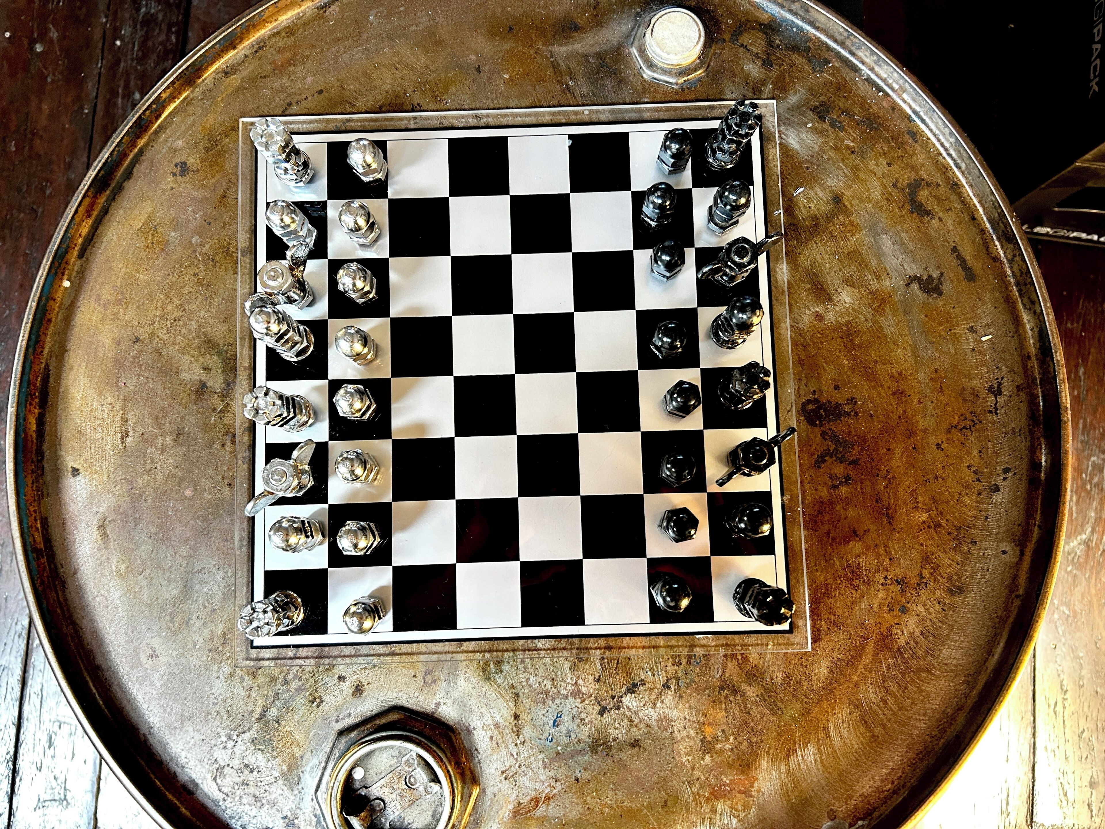 A chessboard with pieces on a metallic surface.