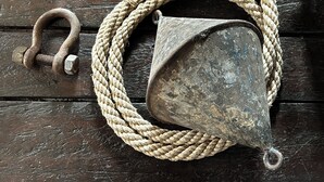 A rope, a metal ring, and a metal bucket on a wooden surface. - Hotelschiff KANAL77 - Schlafen im Hafen (Hamburg)