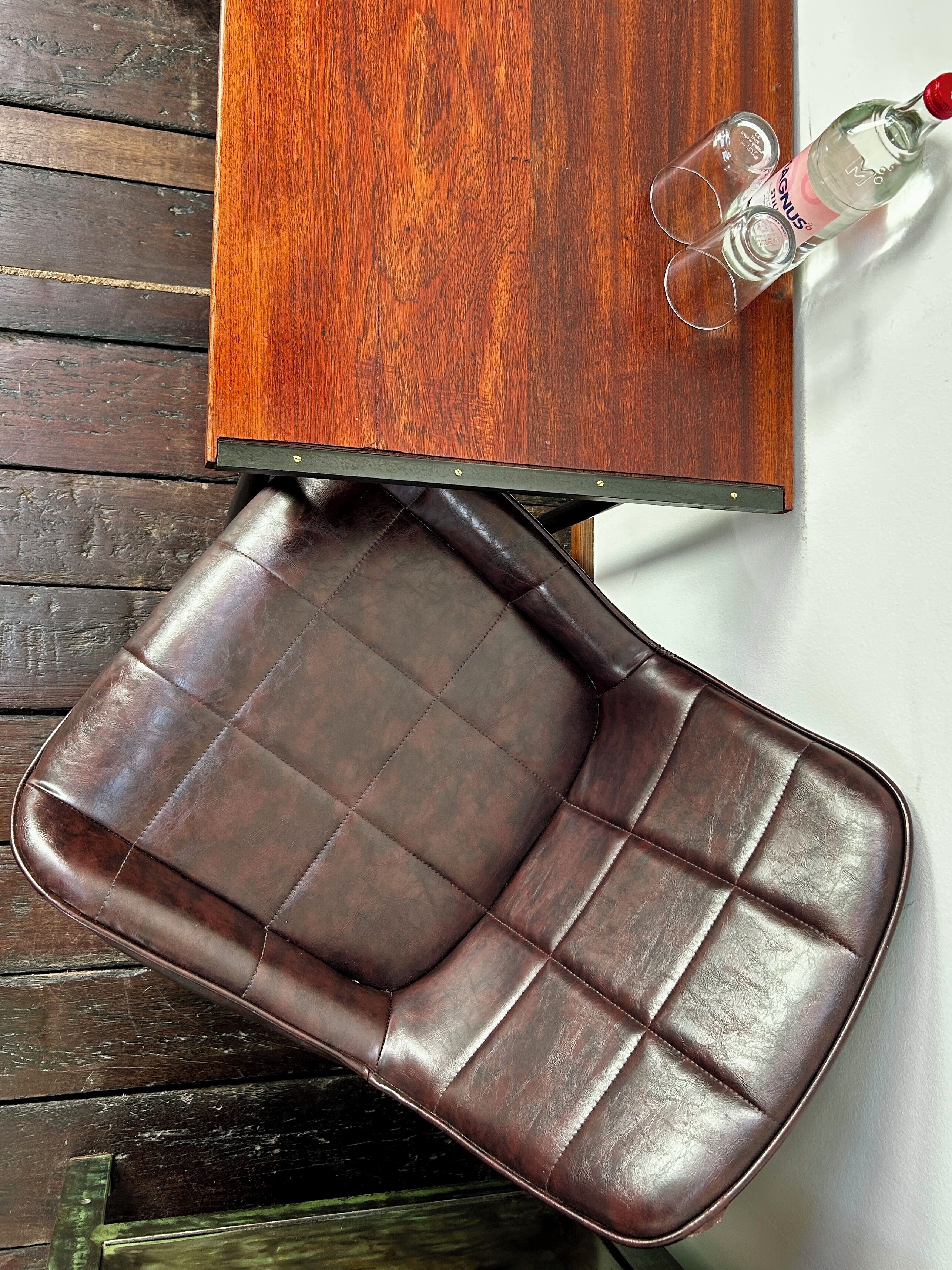 A brown leather bench with a wooden table above it.