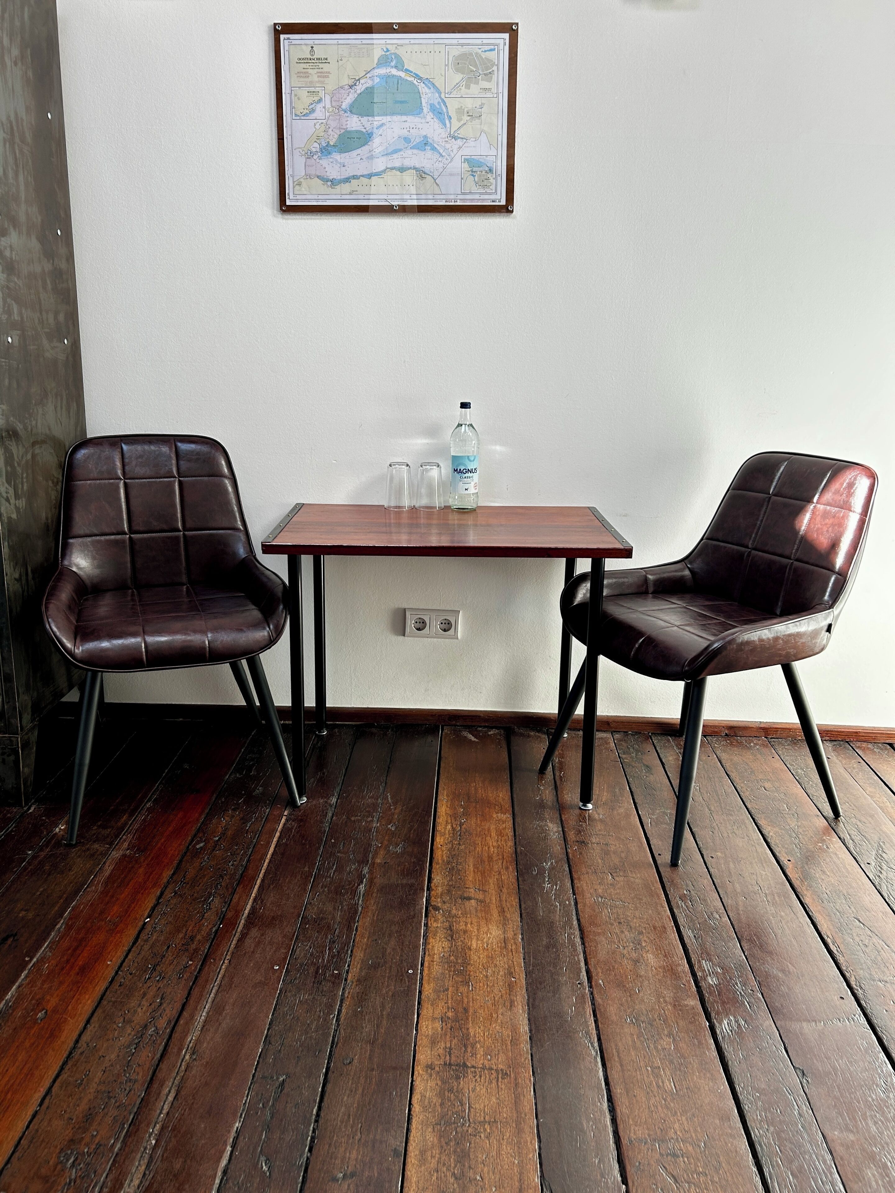 A small room with two leather chairs, a wooden table, and a map on the wall.