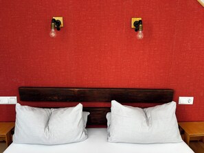 Een bed met witte beddengoed, twee witte kussens, een houten hoofdbord en twee wandlampen.