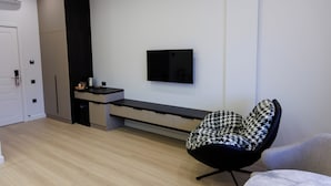 Un ambiente moderno con una poltrona nera, una televisione a schermo piatto e una panca integrata.