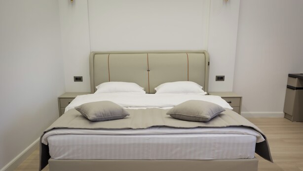 Una camera da letto moderna con un letto grande, due comodini e un tavolino da notte.