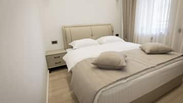Una cama bien hecha con cabecera, dos almohadas y una mesita de noche con cajones.