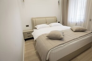 Una cama bien hecha con cabecera, dos almohadas y una mesita de noche con cajones.