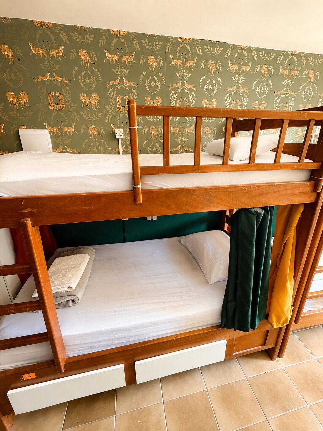 A bunk bed with two levels, a green headboard, and a patterned wallpaper with animal prints.