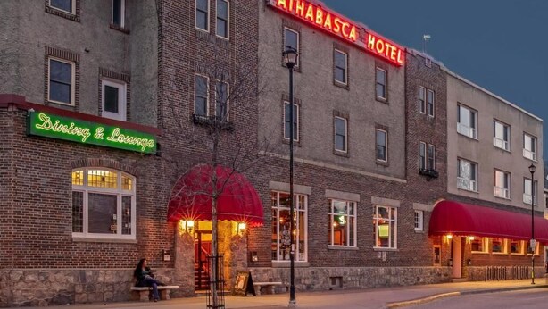 A hotel with a prominent sign reading 'ATHABASCA HOTEL' and a dining area with a red awning. - The Athabasca Hotel (JASPER)