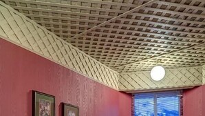 A kitchen with a bar area, white chairs, a window with blinds, and a ceiling with a patterned design. - The Athabasca Hotel (JASPER)