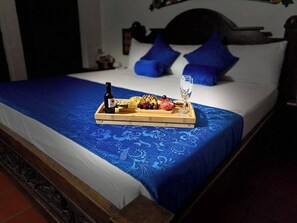 Una cama con una colcha azul, un recipiente con comida y una botella, y un vaso de agua.