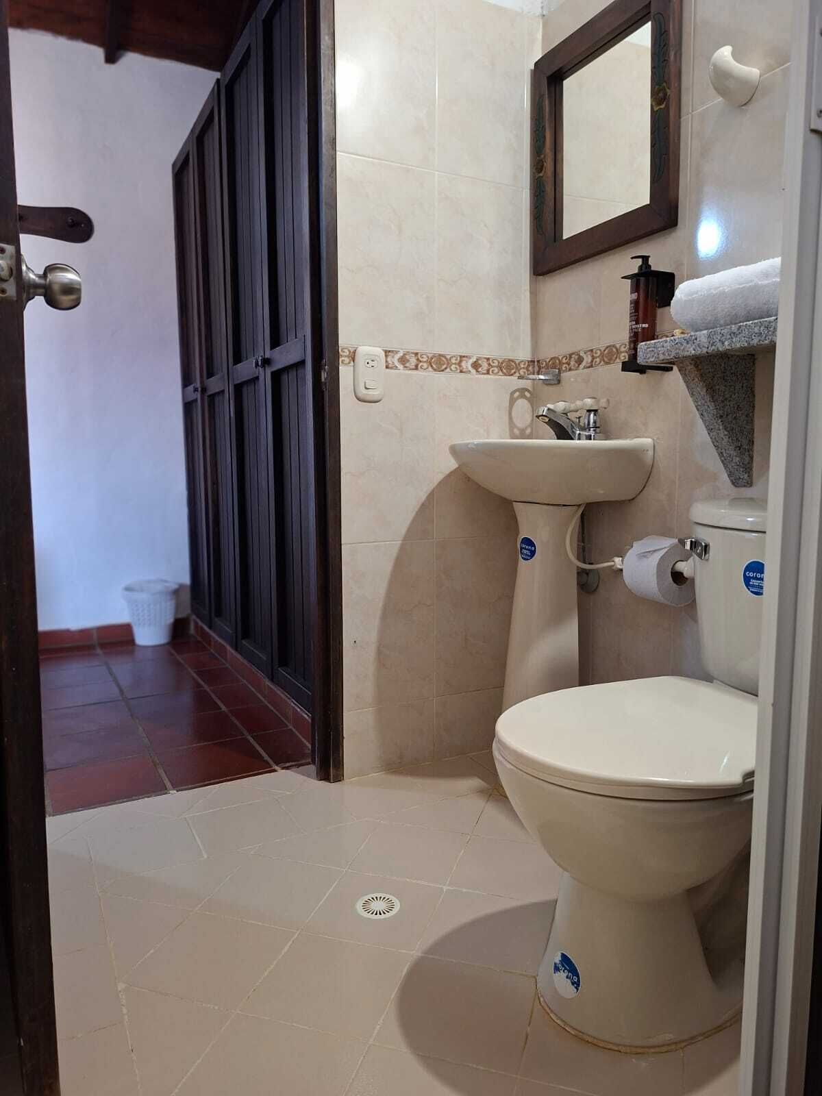 Een badkamer met toilet, wastafel en spiegel.