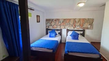 Una habitación con dos camas, una pared de piedra y un suelo de baldosas rojas.