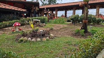 A garden area with a tree, a small pond, and a building with a tiled roof.