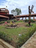 Un jardín con un árbol, un pequeño estanque y un edificio de techo con tejas.