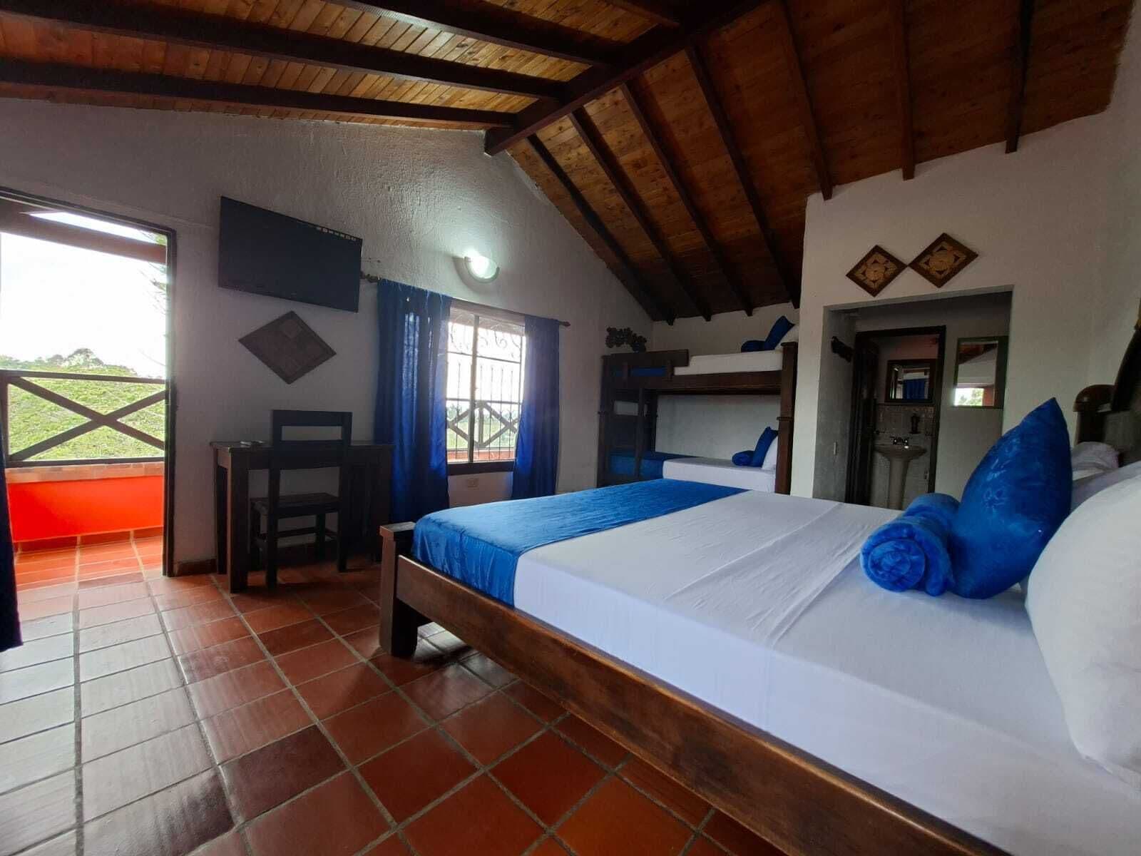 A bedroom with a bed, a desk, and a window.