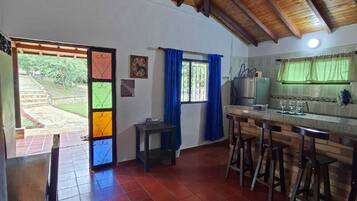 Una cocina con techo de madera, una zona de comedor con mesa y sillas, y vistas al exterior.
