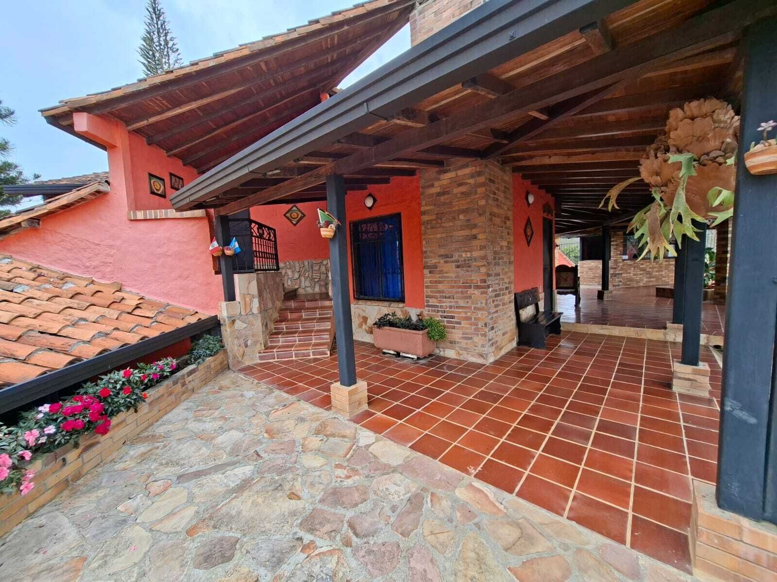 A building with a red facade, a covered patio area with stone flooring, and a blue door.