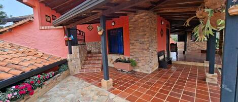 A building with a red facade, a covered patio area with stone flooring, and a blue door.