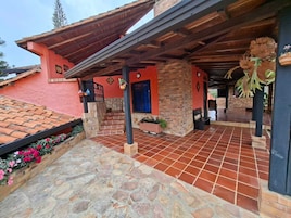 Un edificio con fachada roja, un patio cubierto con suelo de piedra y una puerta azul.