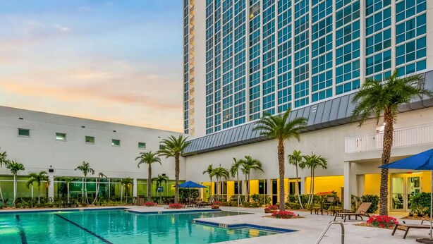 A hotel pool area with a large pool, a hot tub, and palm trees. - Lovely 1-bedroom apartment with AC in Fort Myers (Fort Myers)