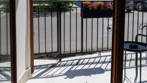 Un balcon avec une balustrade en métal, une chaise et un jardinière.
