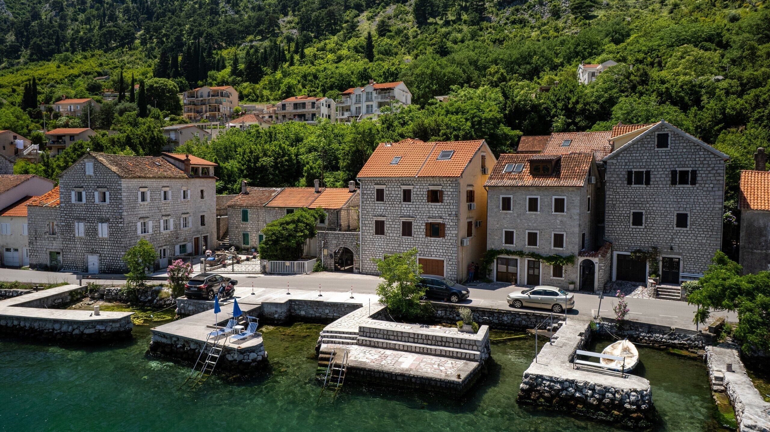 A coastal village with stone buildings, a marina, and clear waters.