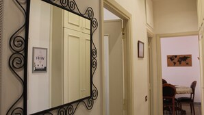 Un couloir avec un grand miroir, une porte donnant sur une salle à manger et une carte du monde accrochée au mur.