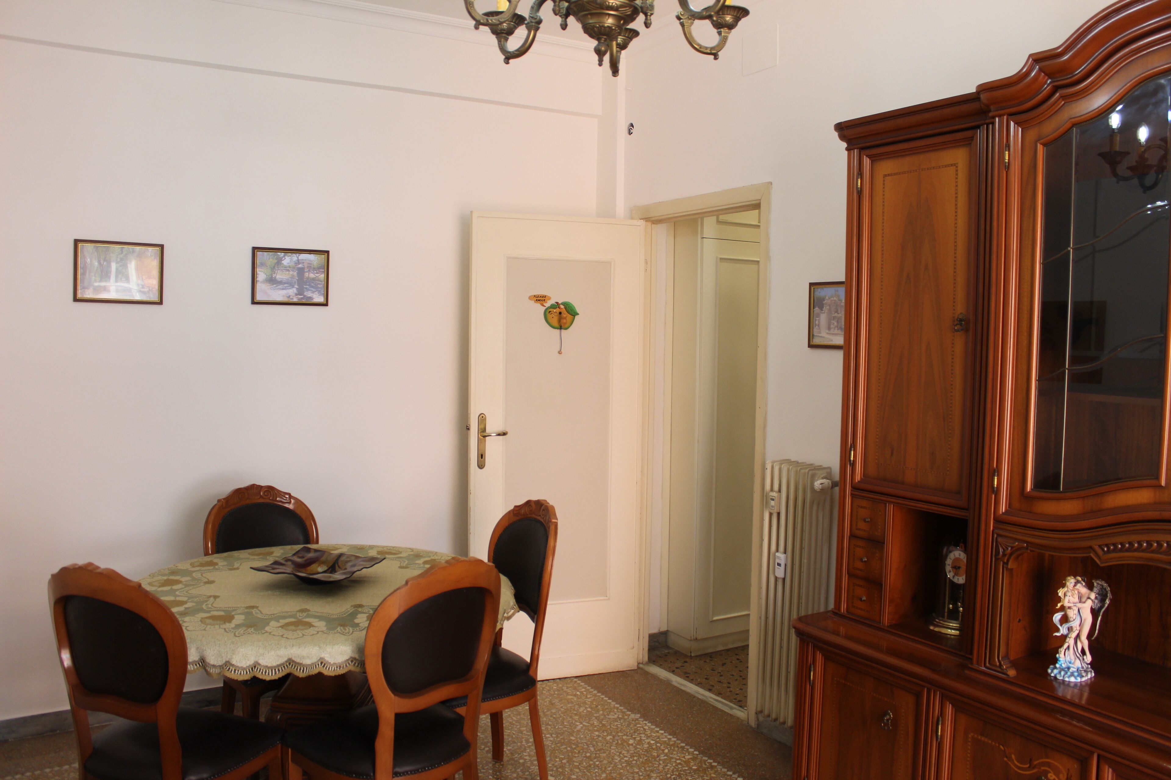 A dining area with a table set for four, a wooden cabinet, and a door leading to another room.