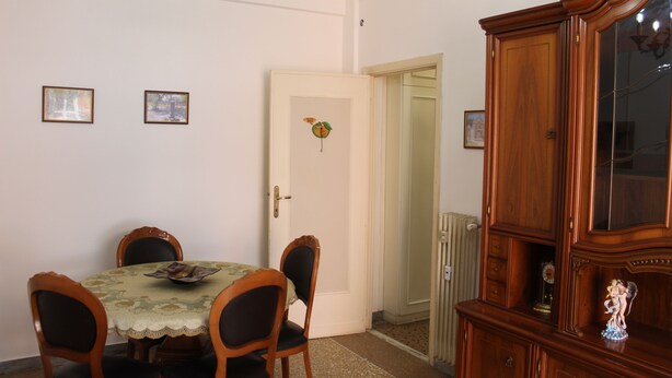 Un coin repas avec une table dressée pour quatre personnes, un buffet en bois et une porte donnant sur une autre pièce.