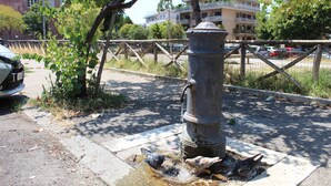 Une fontaine à eau sur un trottoir, avec une clôture en arrière-plan.