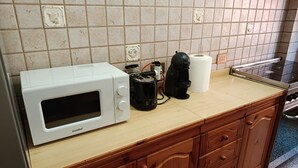 Une cuisine avec un micro-ondes blanc, une machine à café et un rouleau d’essuie-tout posé sur le comptoir.