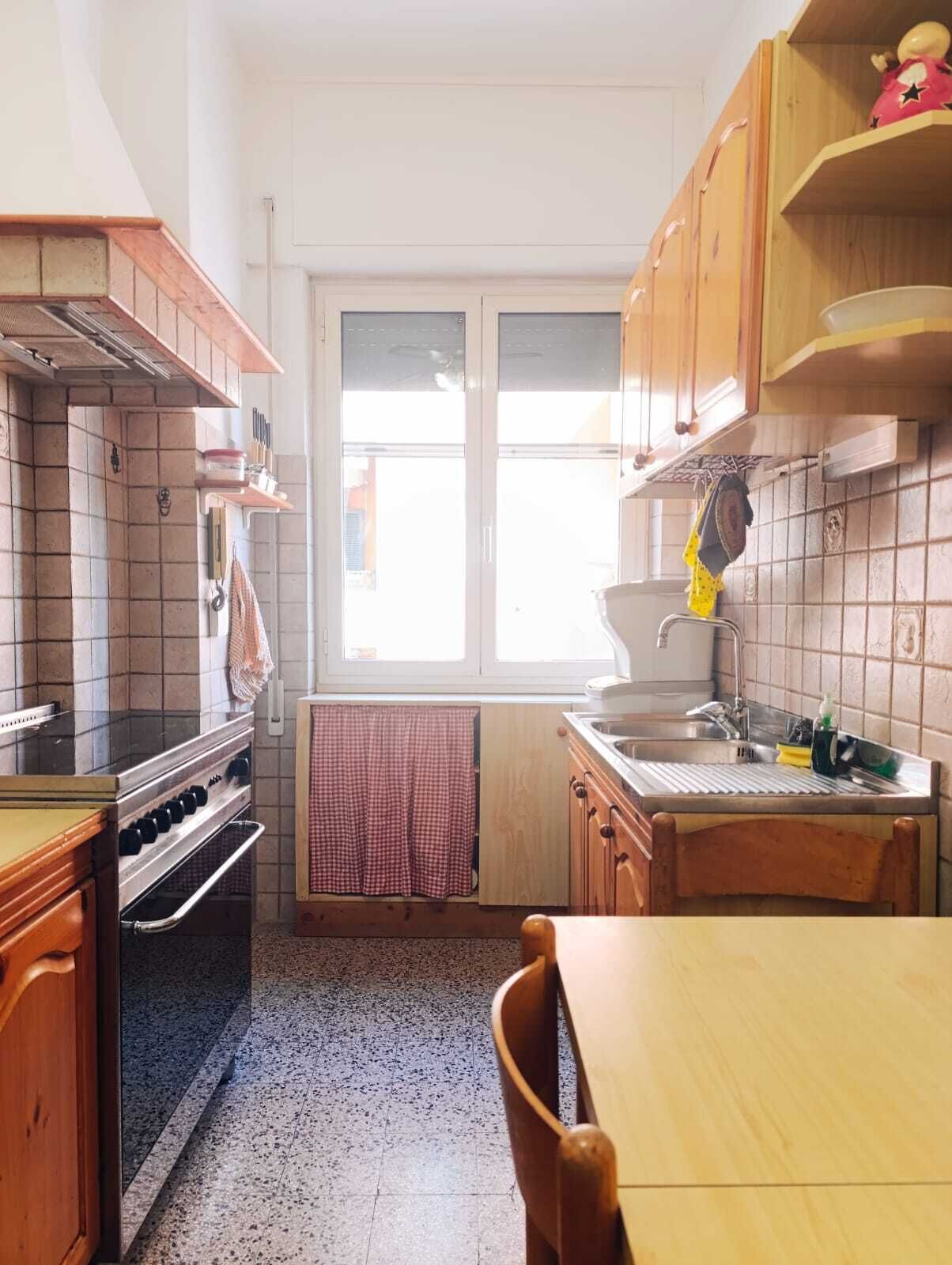 Una cocina con estufa, horno, lavaplatos y ventana.