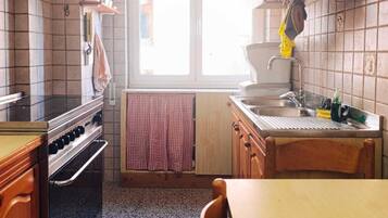 Una cocina con estufa, horno, lavaplatos y ventana.