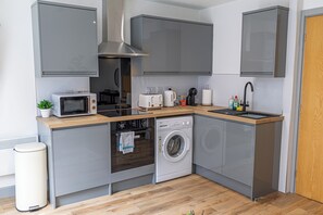Une cuisine compacte équipée d’un four à micro-ondes, d’un grille-pain, d’un évier et d’un lave-linge.