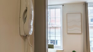 Ein weißes Telefon an der Wand, im Hintergrund ein Fenster und ein gerahmtes Bild.