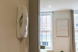 Ein weißes Telefon an der Wand, im Hintergrund ein Fenster und ein gerahmtes Bild.