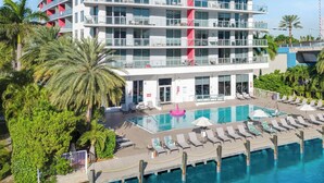 A multi-story hotel with a swimming pool and lounge area. - 1BR North View, Balcony, Resort Pool & Beach (Hallandale Beach)