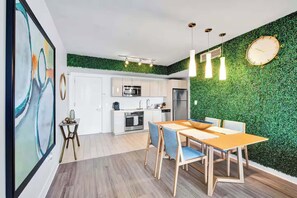 Eine moderne Küche mit weißen Schränken, einem Edelstahlkühlschrank und einer grünen Wand mit einer Uhr.