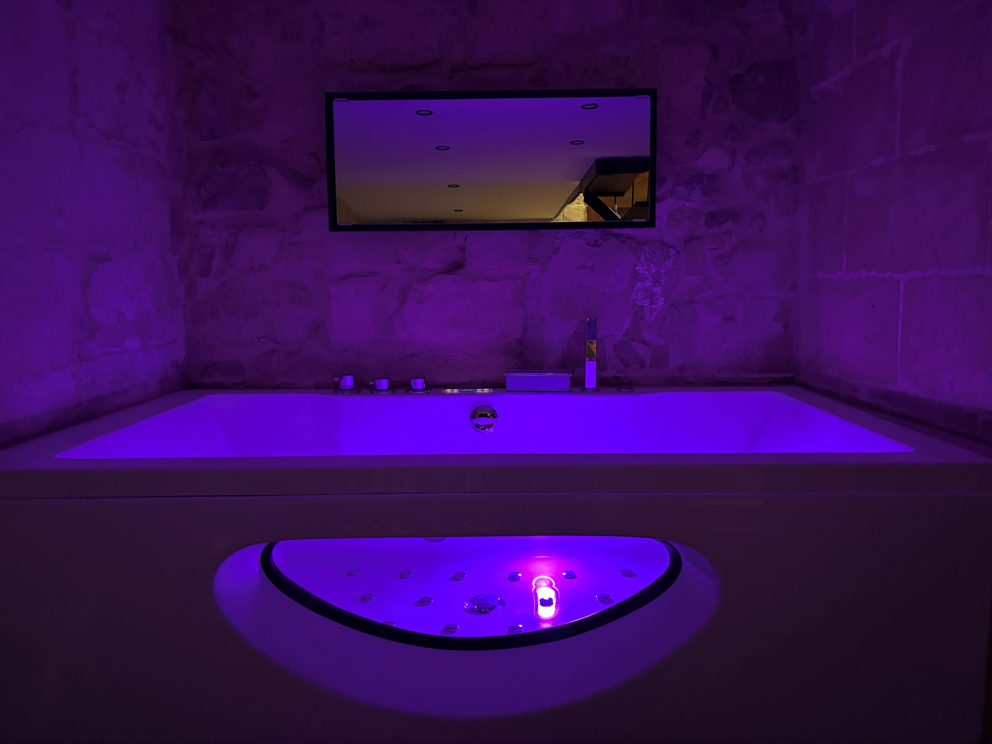 A modern bathroom with a bathtub, a mirror, and a circular light fixture.