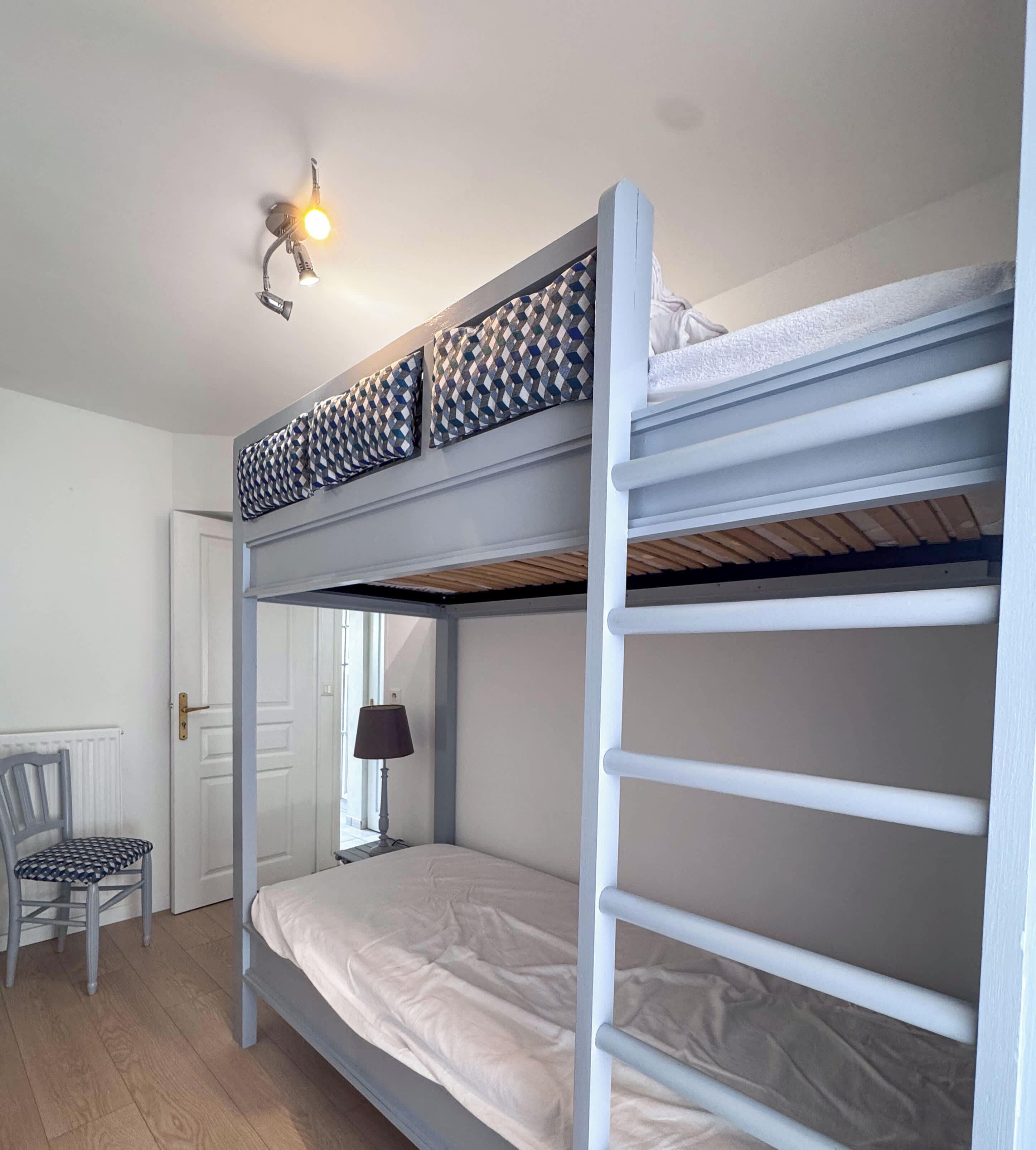 Habitación con literas, escritorio, silla y lámpara.
